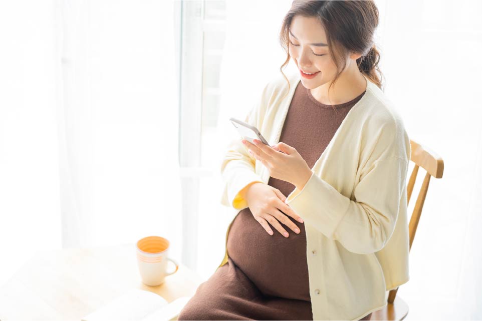 スマートフォンを見ている妊婦