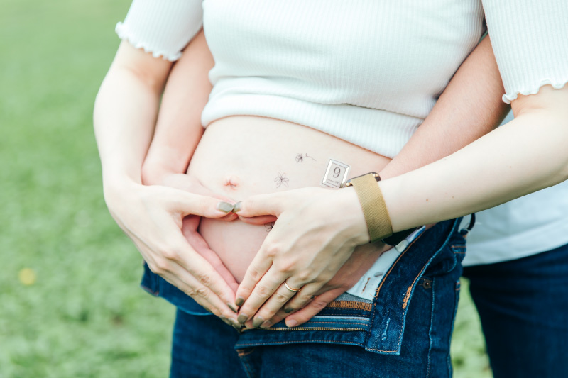 妊婦さんのお腹に男性と女性が手でハートを作っているところです